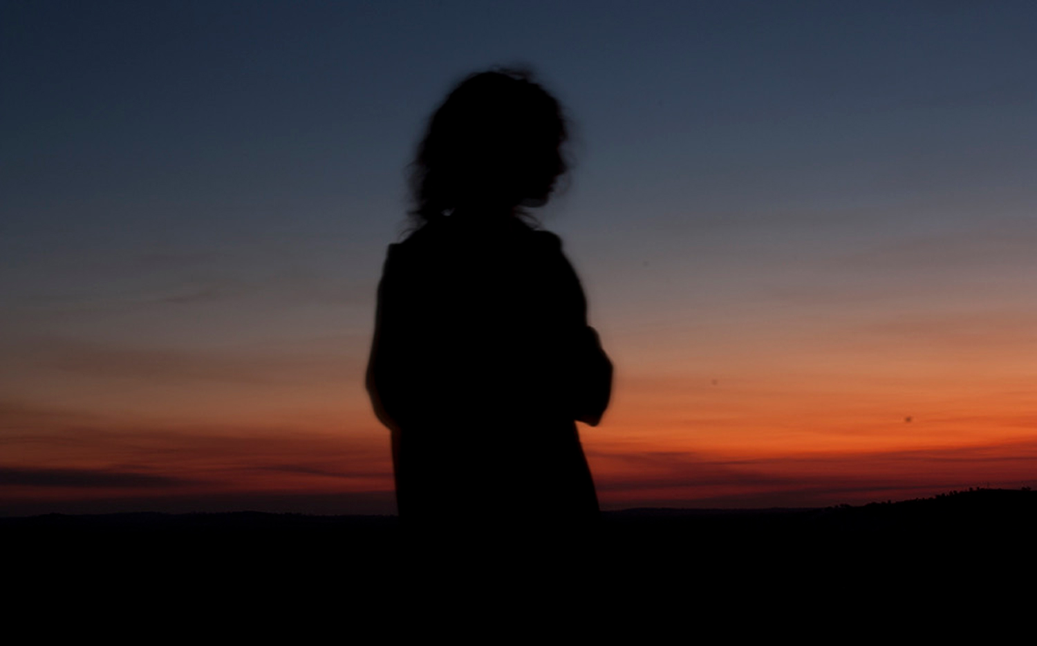Stock image of woman looking onto the sunset.