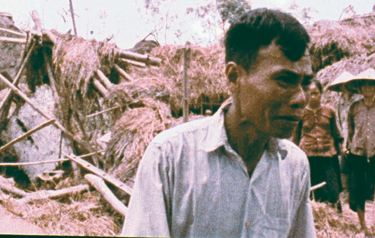 A middle-aged Vietnamese man looks in despair in front of damaged home