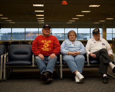 Two older white men and an older white woman sitting in an airport