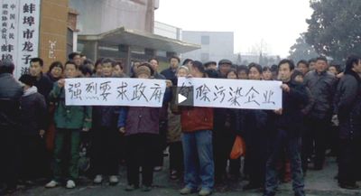A large crowd gathered on a street, holding a banner