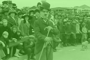 A green overlay on a photo of Charlie Chaplin. In Chaplin's first film, 'Kid Auto Race at Venice' (1914) Mack Sennett's crew went to Venice, California, to shoot a real event.