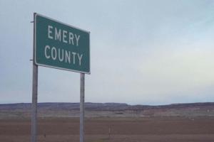 A large empty vista with a single green highway sign reading "Emery County"