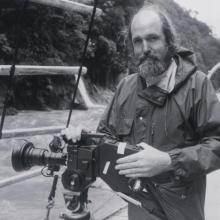 Les Bank, an older white man, holds a camera on a boat.