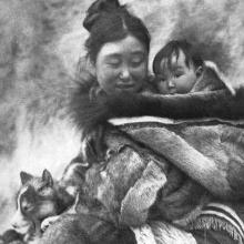 A woman looks over her shoulder at the child she's carrying on her back, from Robert Flaherty's 'Nanook of the North' (1922)