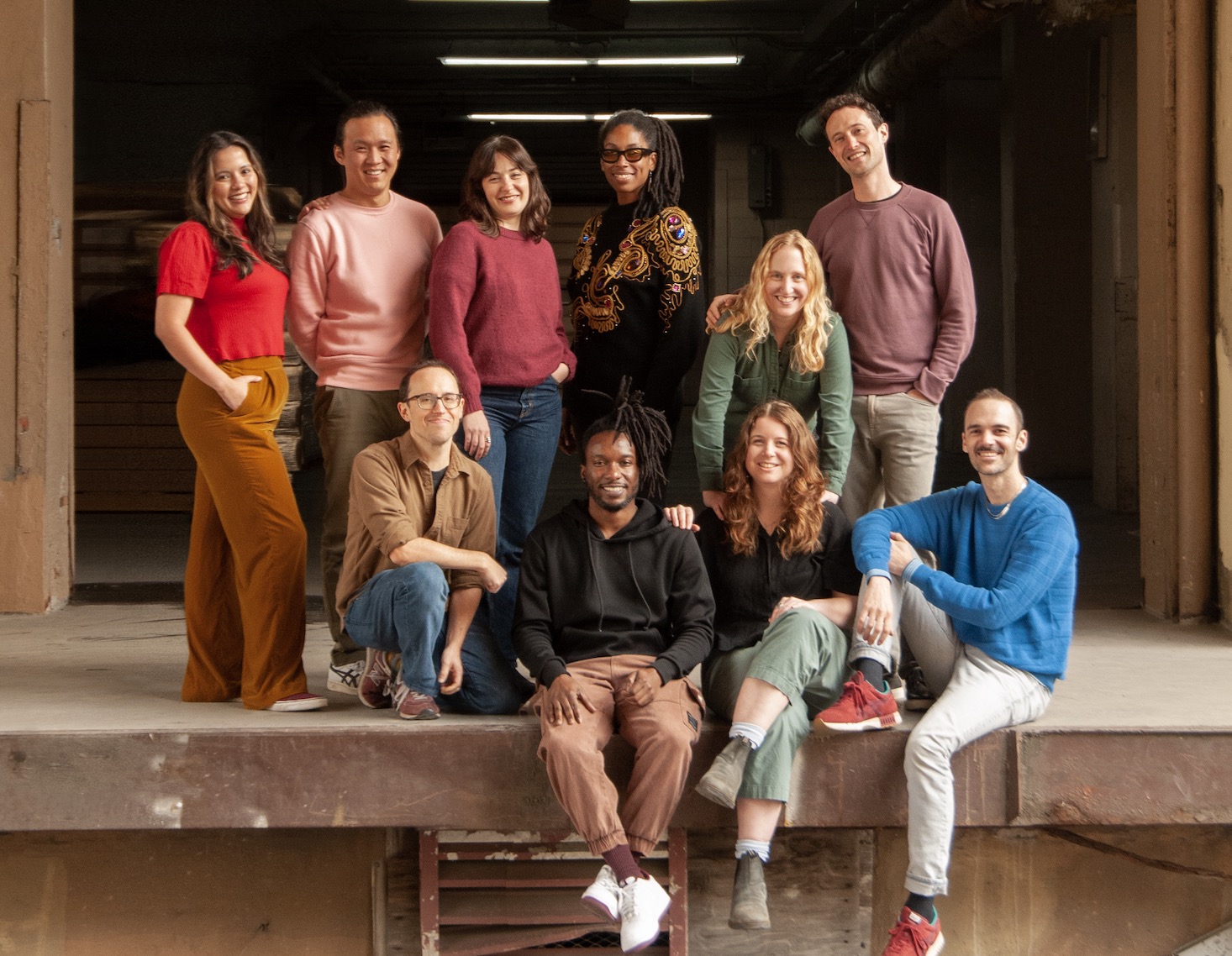 A group photo of ten filmmakers posed in an outdoor, industrial area.