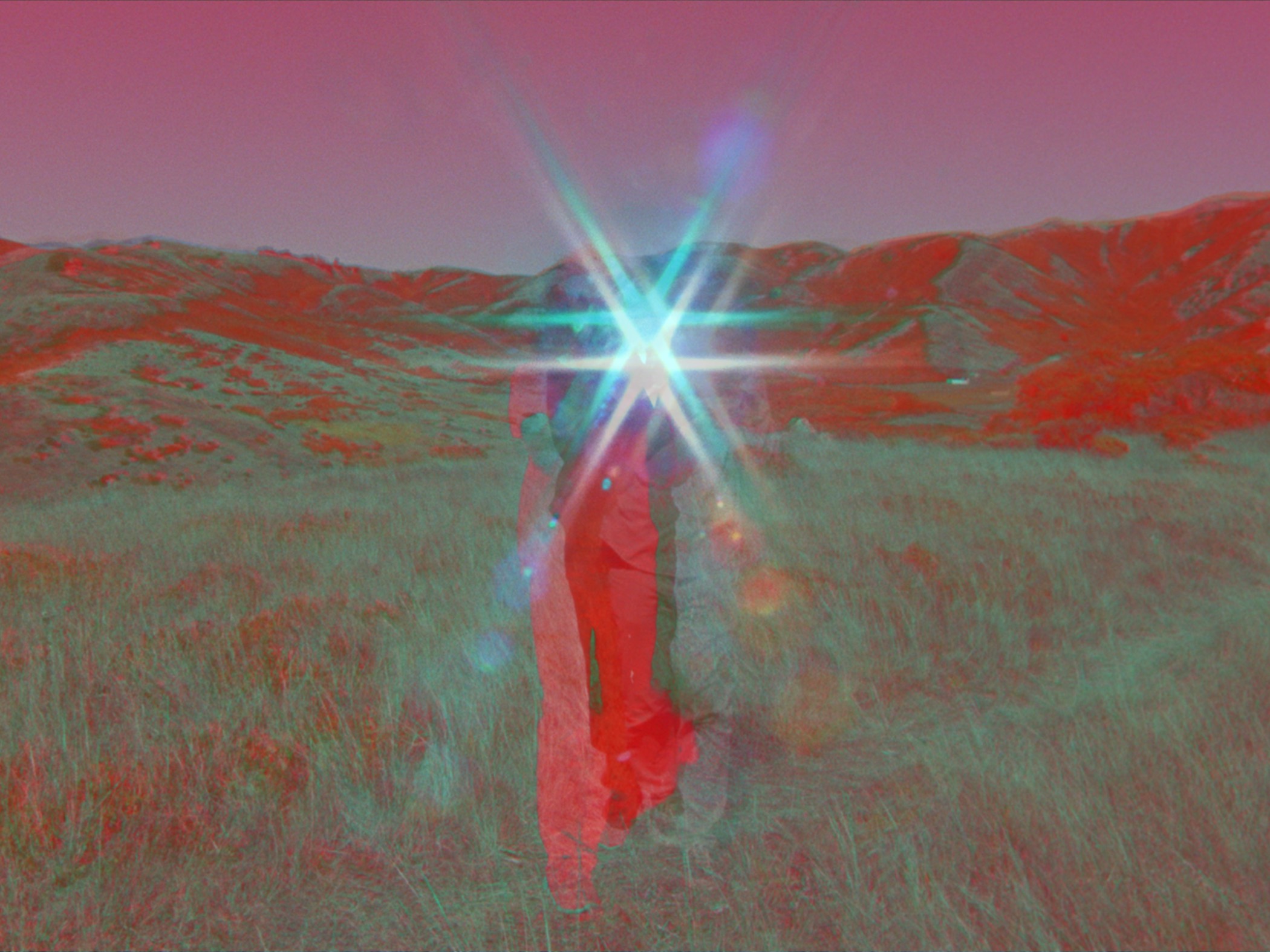 A film still with holographic colors shows a figure in a field.