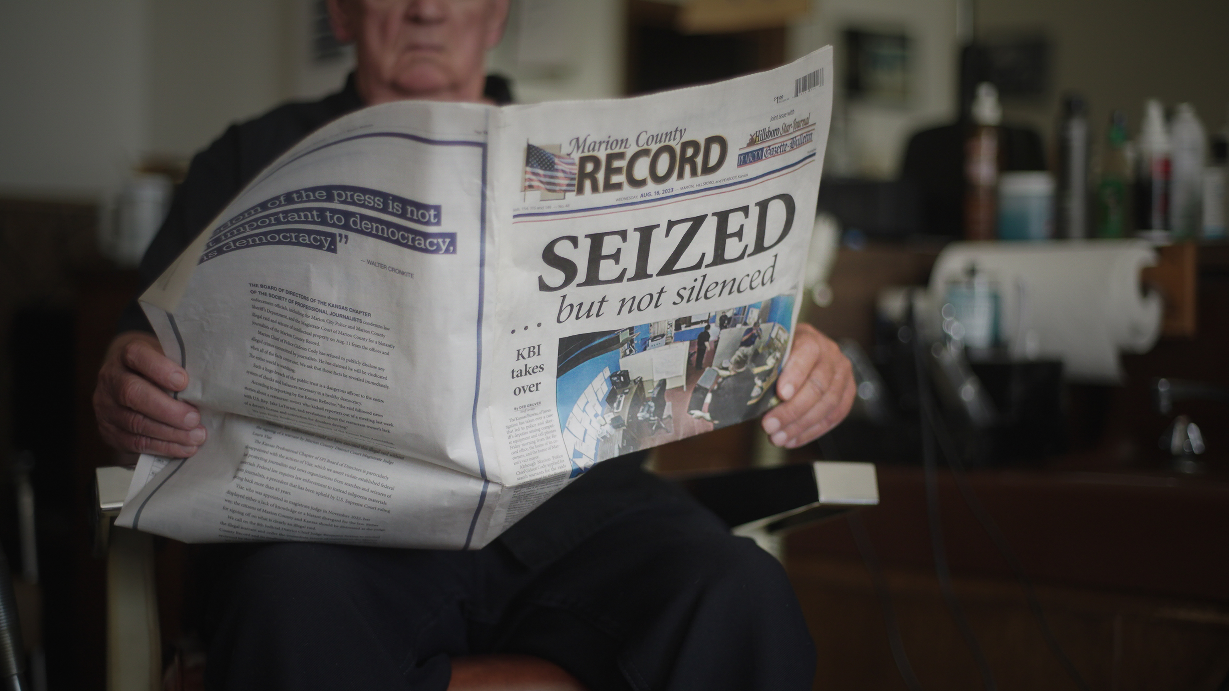 A man holds a newspaper with the headline: "SEIZED."