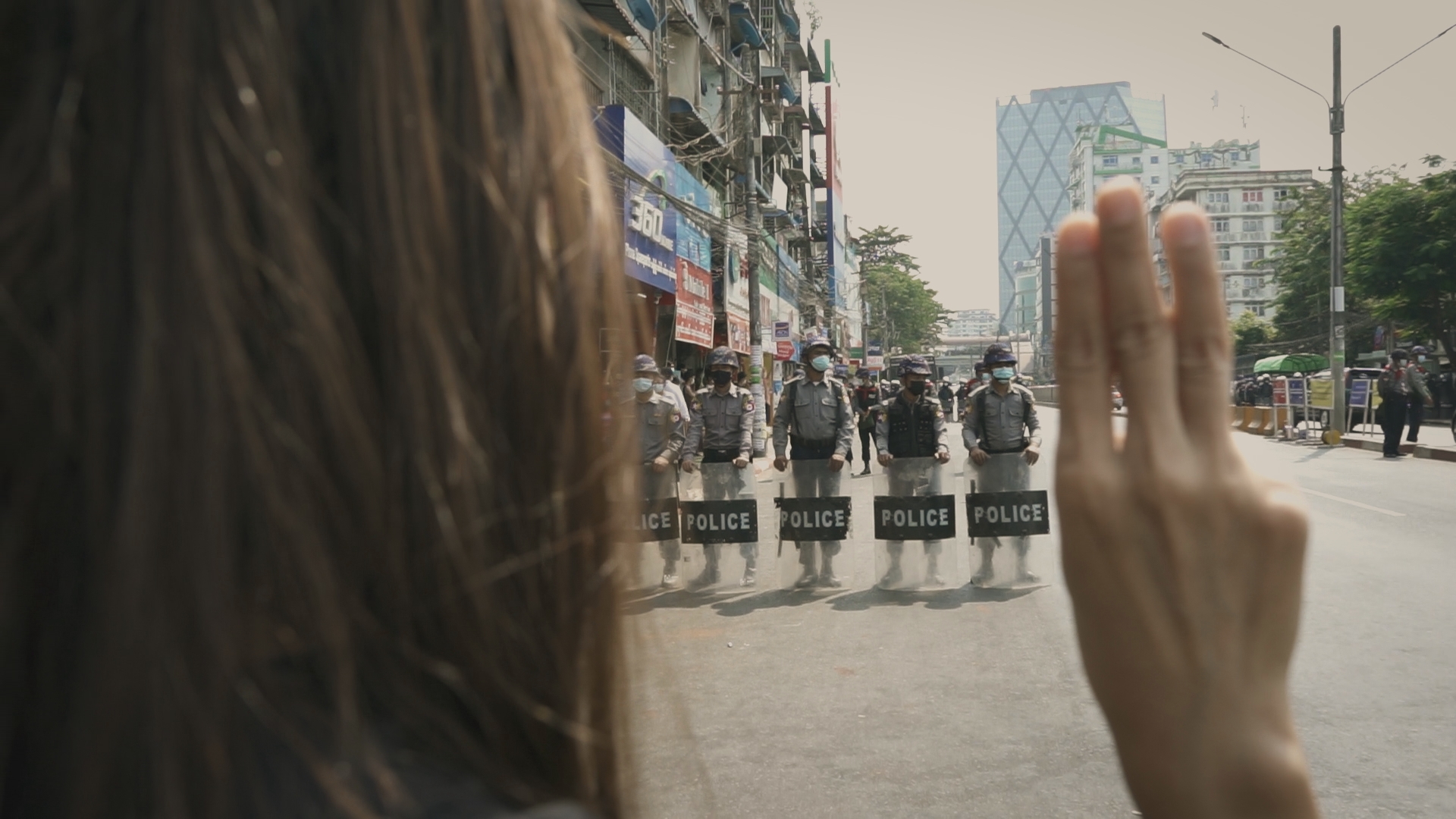 A person holds up three fingers standing in front of a line of police in riot gear. From ‘Myanmar Diaries.’ Photo courtesy of Double Exposure Film Festival