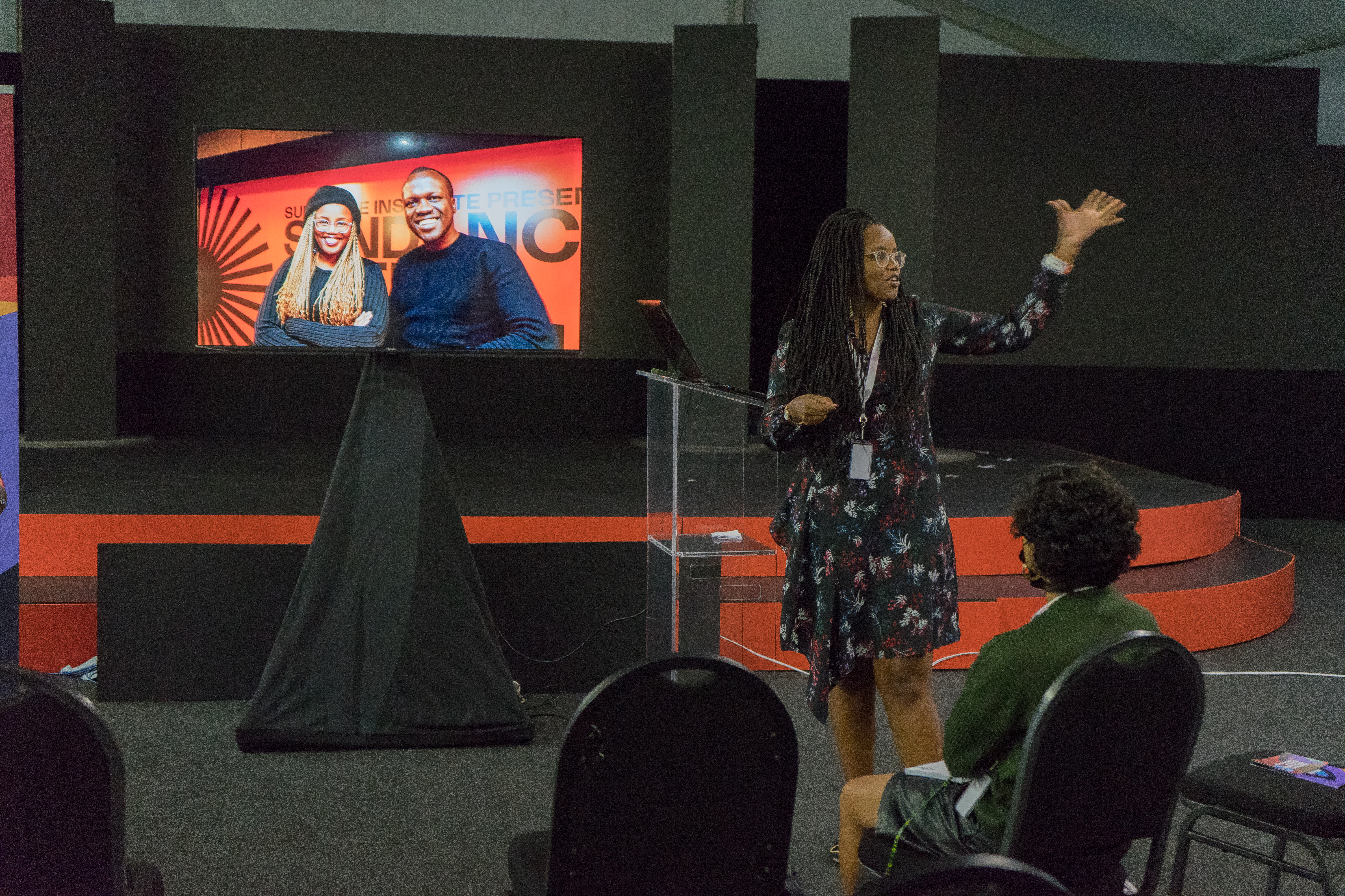 Producer Toni Kamau, an African woman with long braids, glasses and a floral print dress, at Docubox masterclass at Creative Africa Nexus. Photo courtesy of Docubox. 