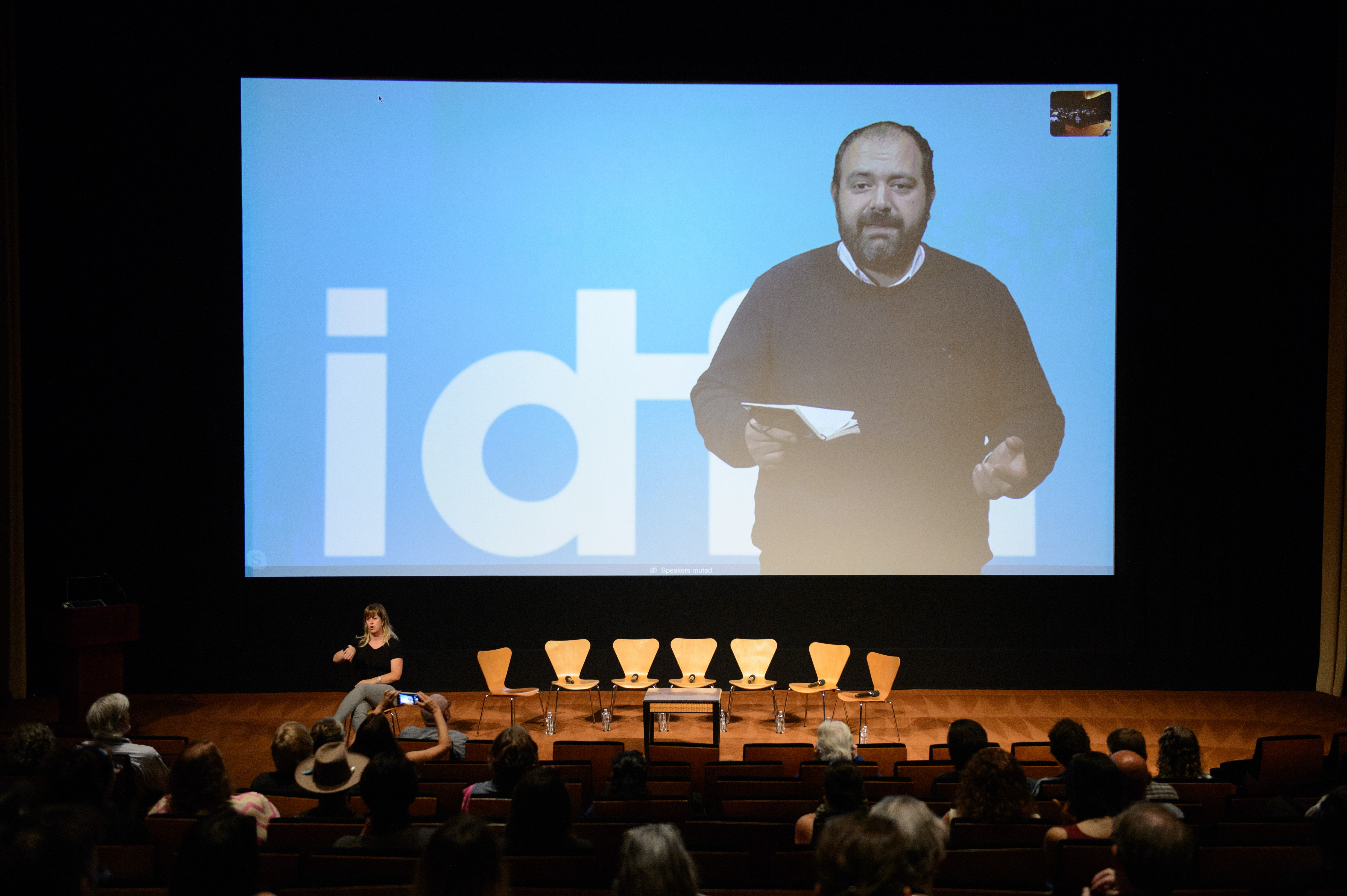 IDFA Artistic Director Orwa Nyrabia, shown delivering a keynote address on a large screen at the 2018 Getting Real conference, is a Syrian man with a beard, wearing a dark sweater. Photo courtesy of AMPAS