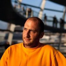 Portrait of Alon Schwarz wearing an orange sweater