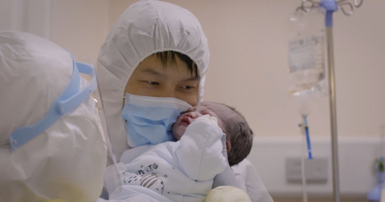An Asian man, wearing a protective hood and mask, holds his newborn baby. From Yung Chang's 'Wuhan Wuhan."  Courtesy of Stars Collective Films Entertainment Group, Inc.
