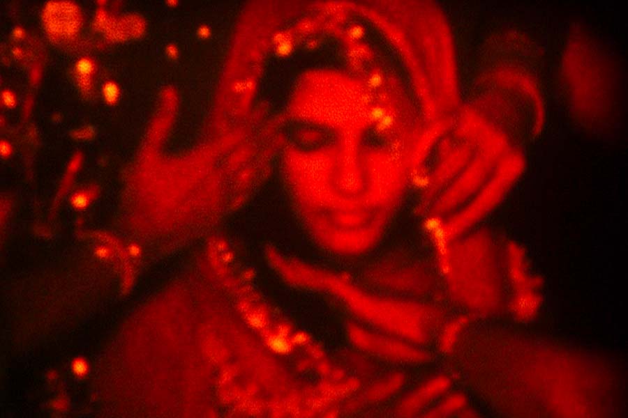 A red filtered image of a South Asian bride. She is wearing a veil. From Payal Kapadia’s ‘A Night of Knowing Nothing.’ Courtesy of TIFF
