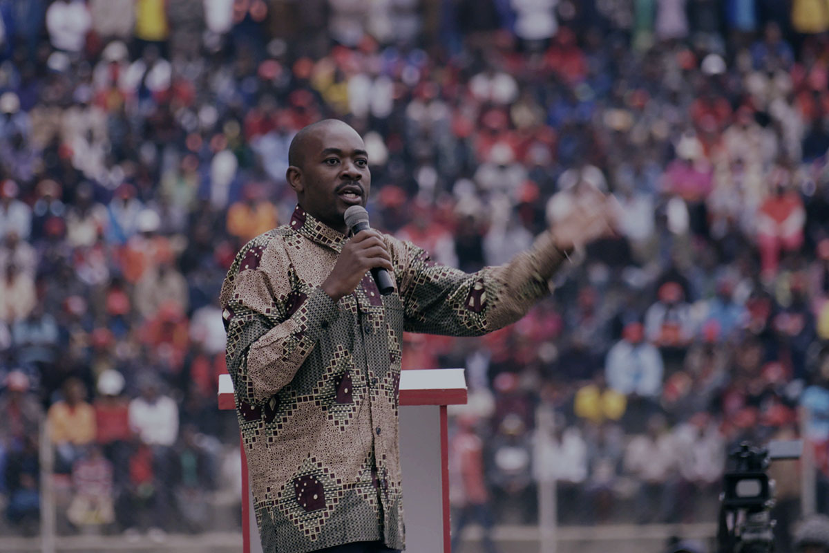 Nelson Chamisa is a bald Zimbabwean male politician wearing a patterned brown shirt. He is addressing a crowd of people. Image from Camilla Nielsson’s ‘President.’ Photo by Henrik Bohn Ipsen. Courtesy of Greenwich Entertainment.