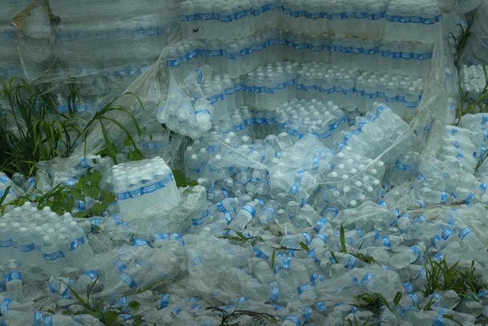 Hundreds of undistributed plastic bottles of water lying on the ground in Puerto Rico. Image from “Landfall” directed by Cecilia Aldarondo. Photo by Pablo Alvarez-Mesa. Courtesy of POV