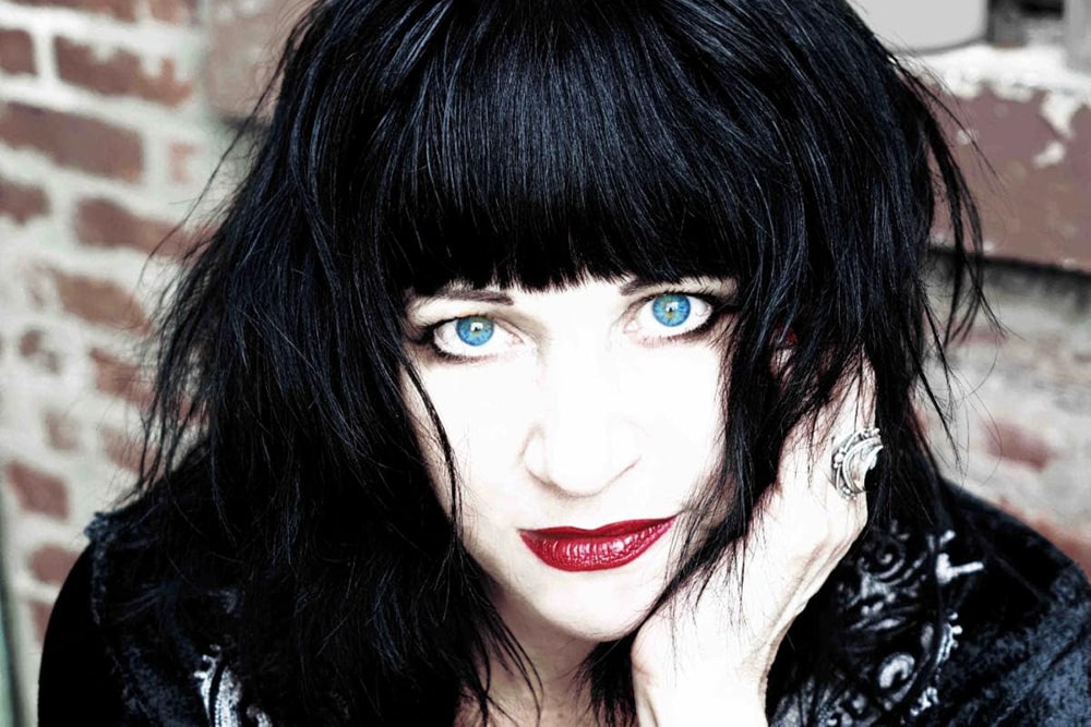 Lydia Lunch, a white woman with black hair cut in bangs. She is wearing bright blue contact lenses and red lipstick. From Beth B’s ‘Lydia Lunch: The War is Never Over’. Courtesy of Kino Lorber.