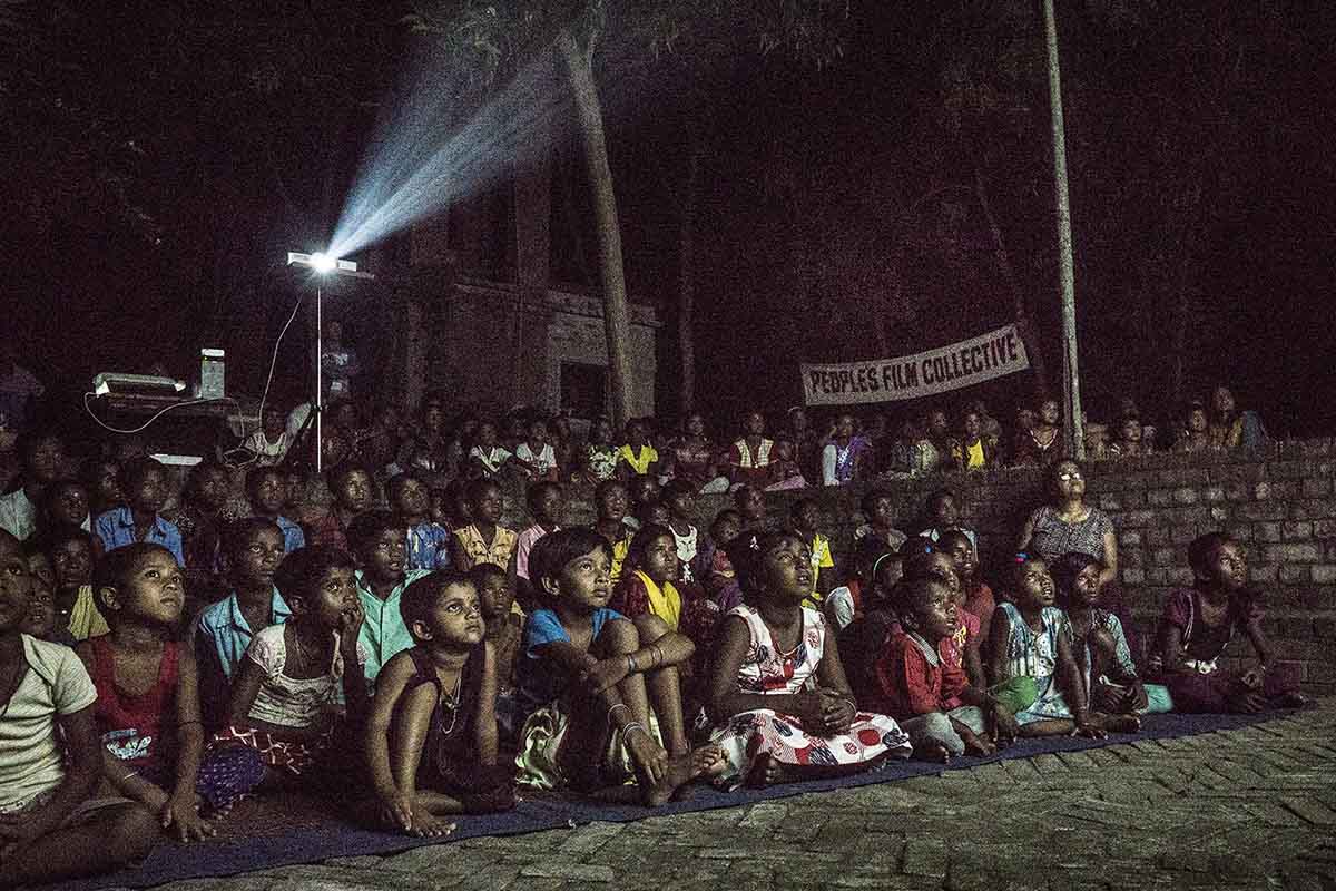 A group of Indian children and adults gathered together at night, for a film screening organized by the People's Film Collective. Photo courtesy of People's Film Collective.