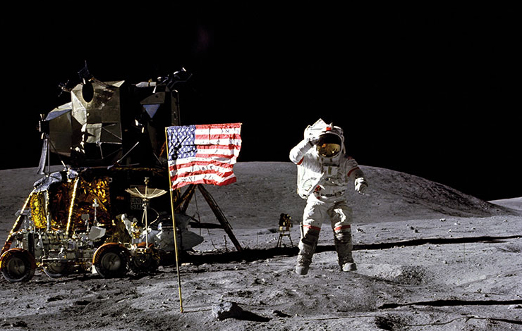 An astronaut salutes while standing next to the American flag on the moon. From Al Reinert's For All Mankind, the film looks at man's first lunar voyage, as told by the men who traveled there and back.