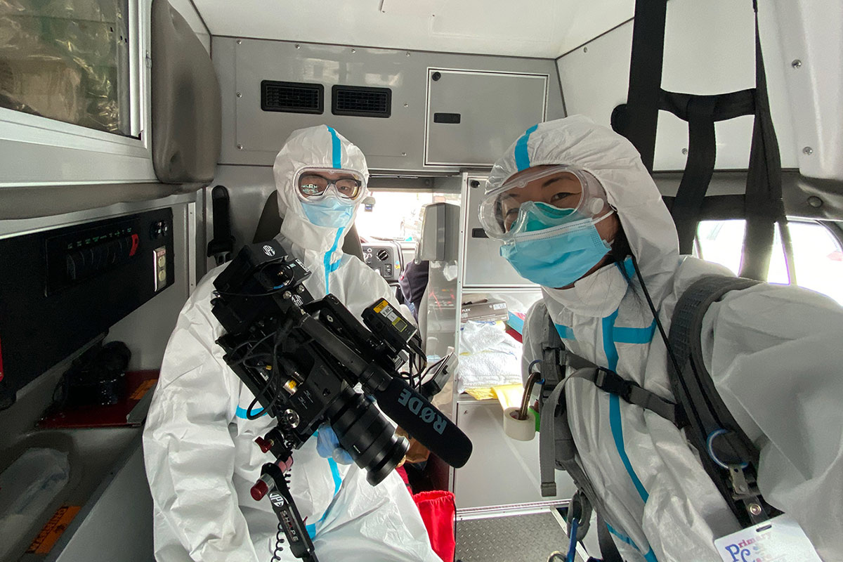 two filmmakers in PPE gear inside a van