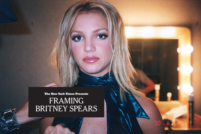 Britney Spears is looking at the camera in a dressing room, wearing a sparkling blue halter top