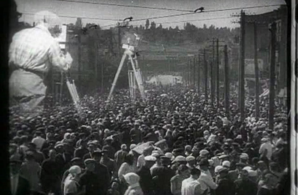 A black-and-white image of a filmmaker looming over a crowd of people. From Dziga Vertov’s ‘Man with a Movie Camera.’ Courtesy of Criterion Collection.