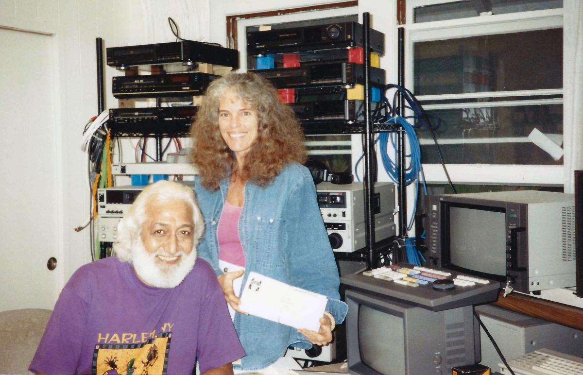  Puhipau, a Hawaiian man with a moustache and beard, and Joan Lander, a white woman in a denim shirt, smile in front of their editing equipment, in1994. Photo by Huong Doan.