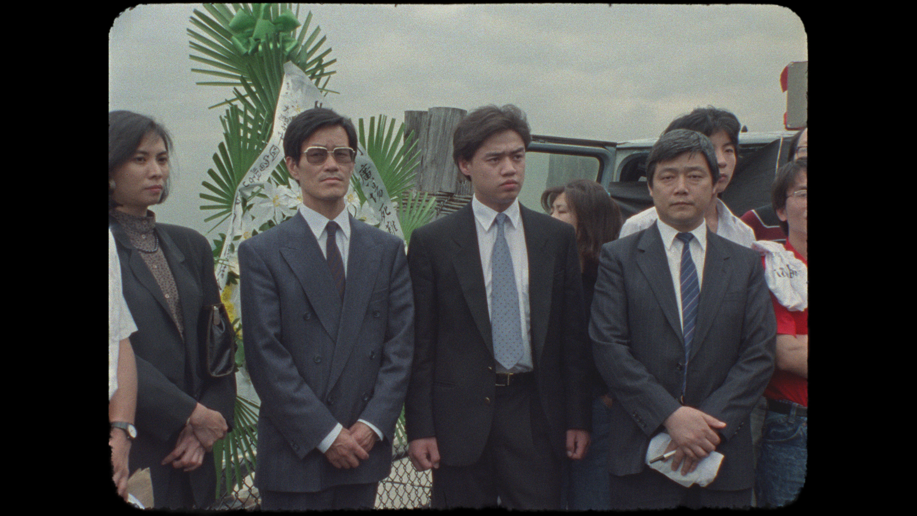 Four Chinese dissidents--one woman and three men--dressed in suits, stand in New York City's Battery Park. From 1989 footage from the suspended project 'Tiananmen/China Today.' Courtesy of Christine Choy 