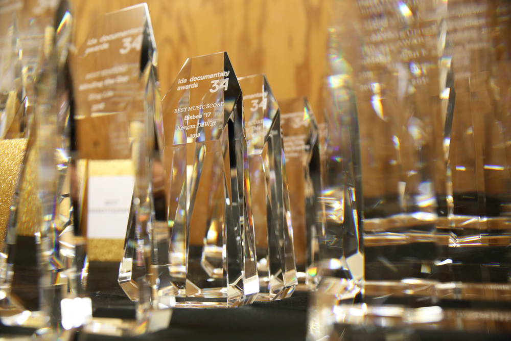 Trophies from the 34th Annual IDA Documentary Awards are lined up on a shelf.