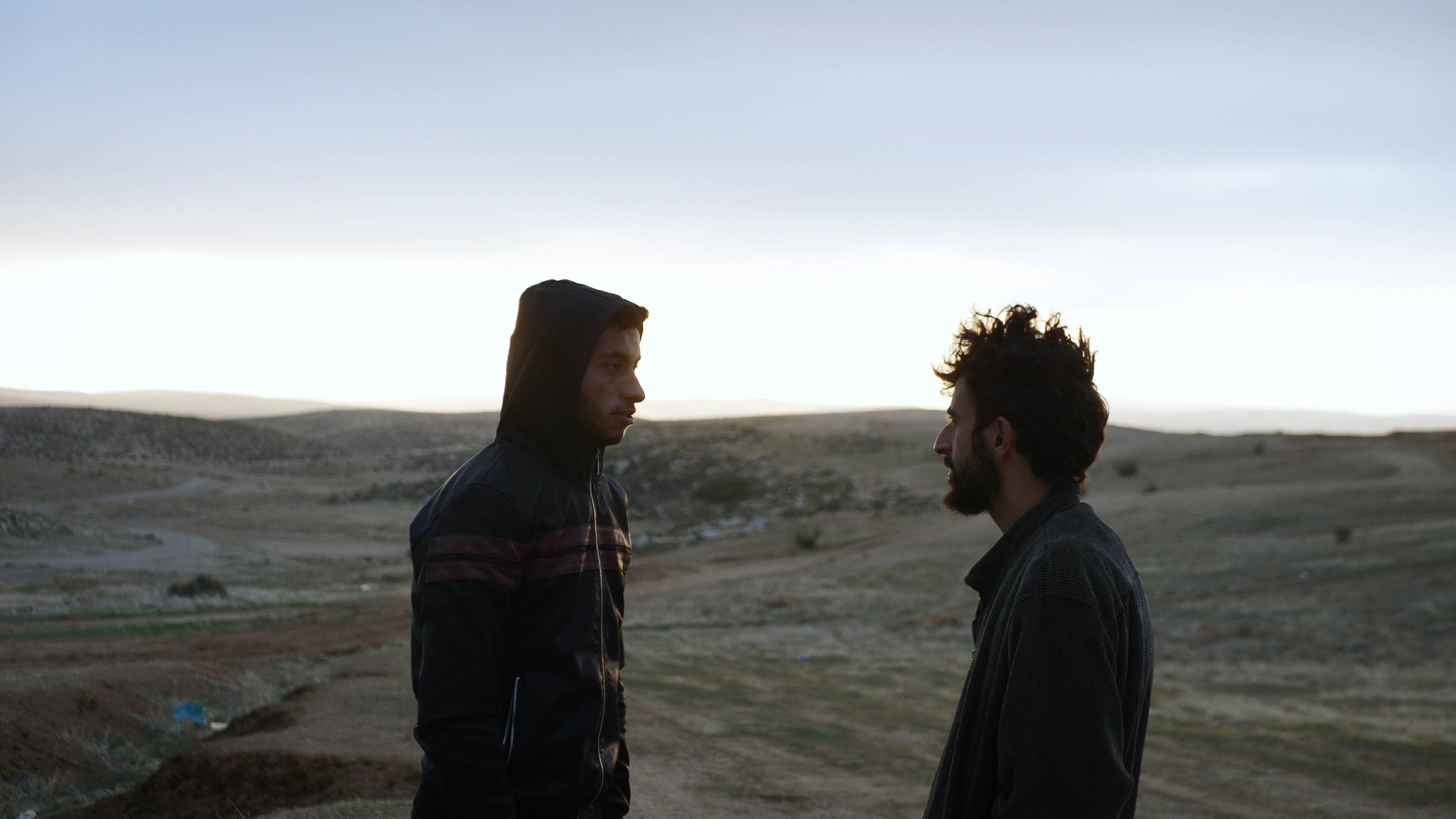 Two young men look at each other.