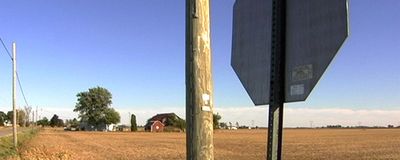 Back of a stop sign with a field in the background