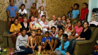 Large group of adults and children posed on and around a couch for a family photo