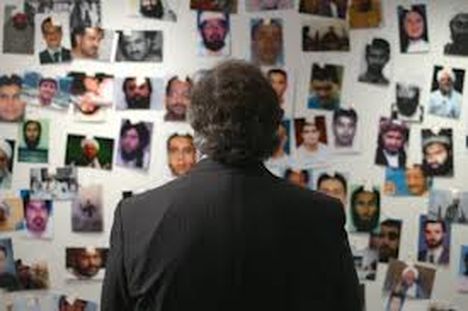 The back of the head of a man with curly gray hair, studying a board with images taped up