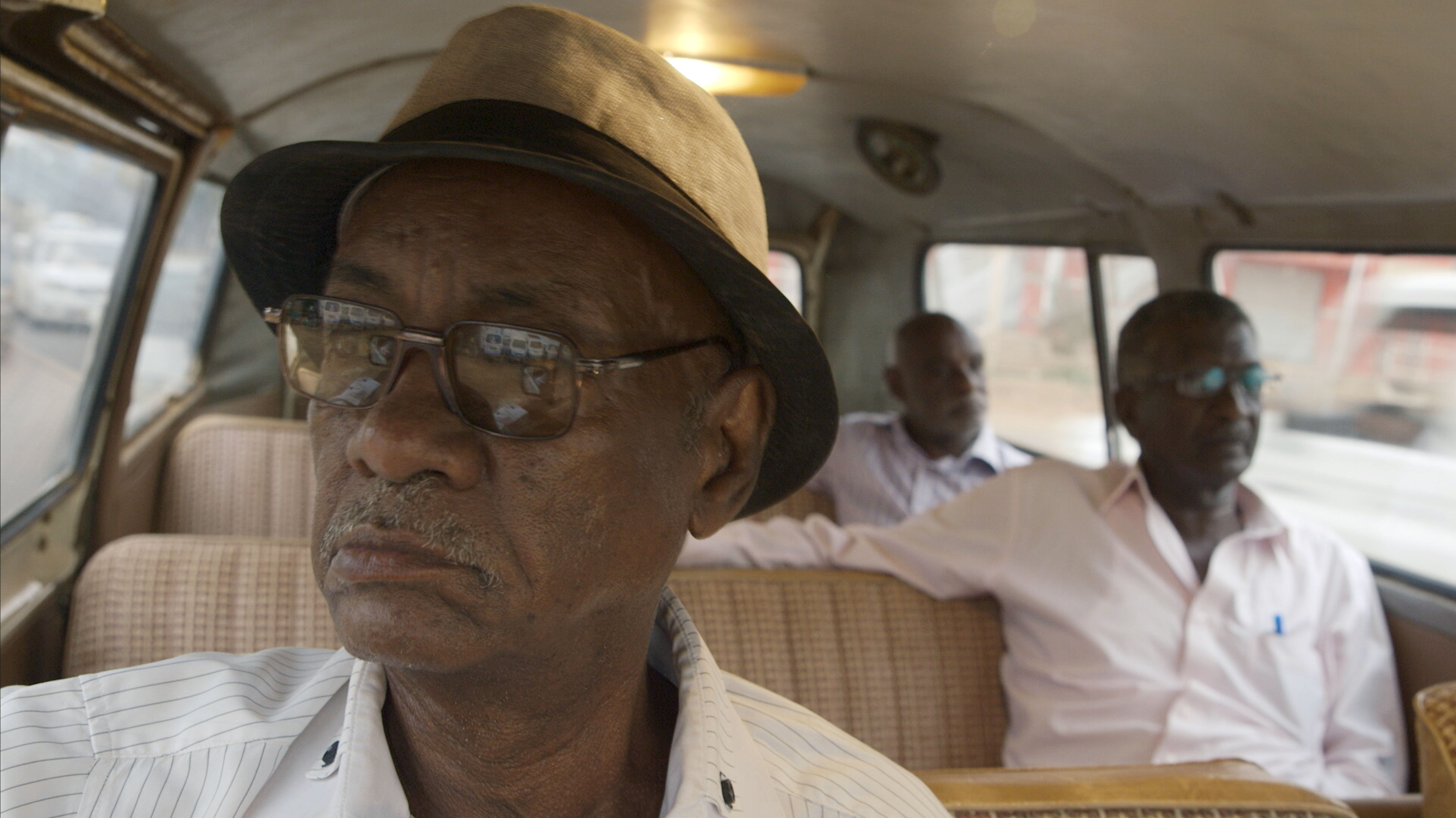 Three older filmmakers sit in a van.