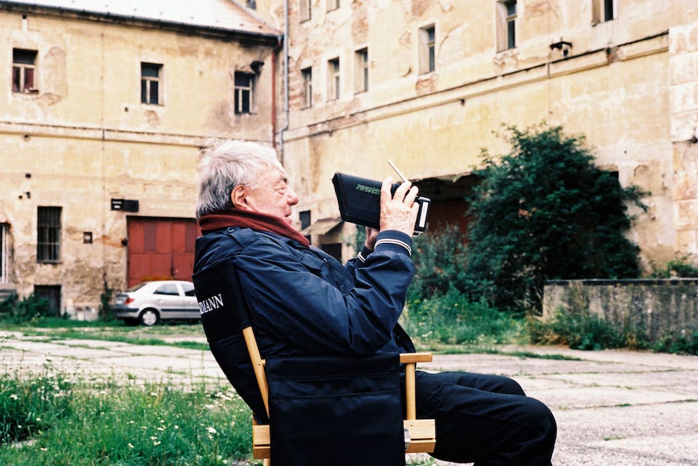 Claude Lanzmann sits in a director's chair.