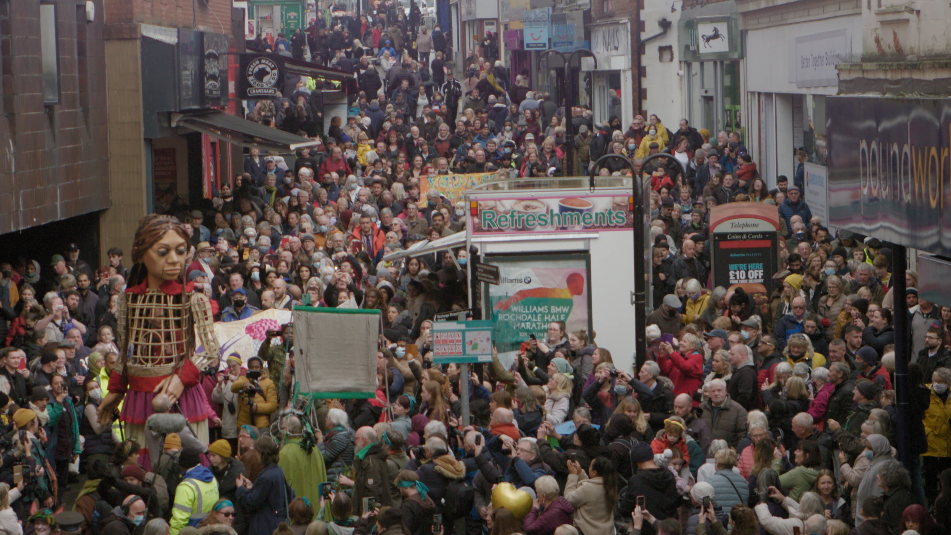 Film still from ‘The Walk,’ depicting a giant puppet in a large crowd. Courtesy of Grain Media of Grain Media