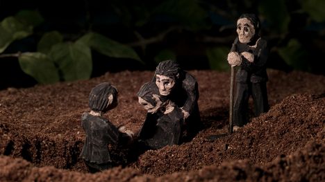 Three clay figures in black cloaks burying a fourth clay figure