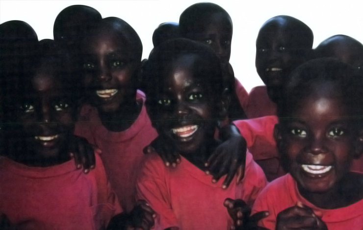 A group of children wearing matching red shirts smile at the camera.