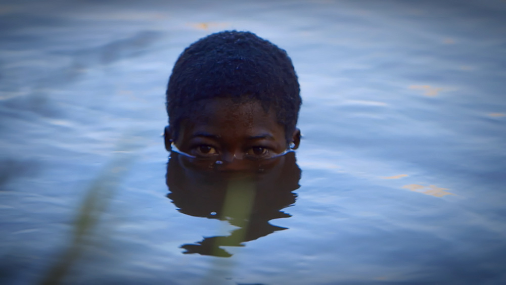 The face of a young Black boy half-submerged in water. From Michele Stephenson's  'Stateless.' Courtesy of National Film Board, Canada.