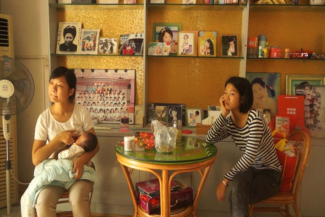 Li Wang, a young Chinese woman, breastfeeds her infant son, Wenjie Zheng, as she sits next to her sister Jin Zhou. From Wang Qiong’s ‘All About My Sisters.’ Courtesy of the dGenerate Collection at Icarus Films.