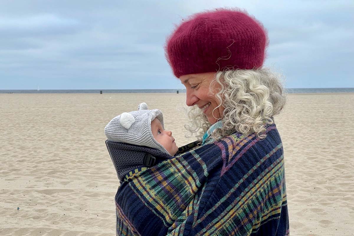 Filmmaker Helen Hood Scheer is a white woman carrying her baby, Maude. They're both on a beach. Courtesy of Helen Hood Scheer.