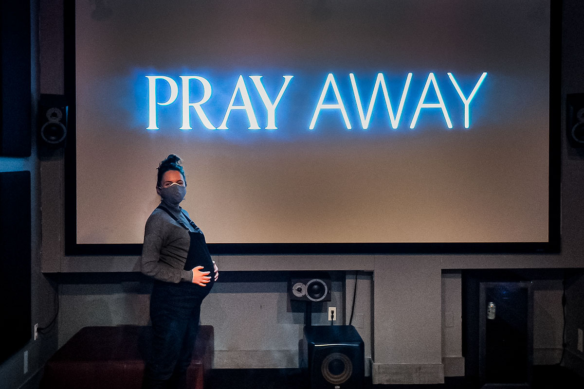 Filmmaker Kristine Stolakis, 8 months pregnant, is a white woman wearing black overalls on the last day of color correction of her film 'Pray Away.' Courtesy of Kristine Stolakis. 