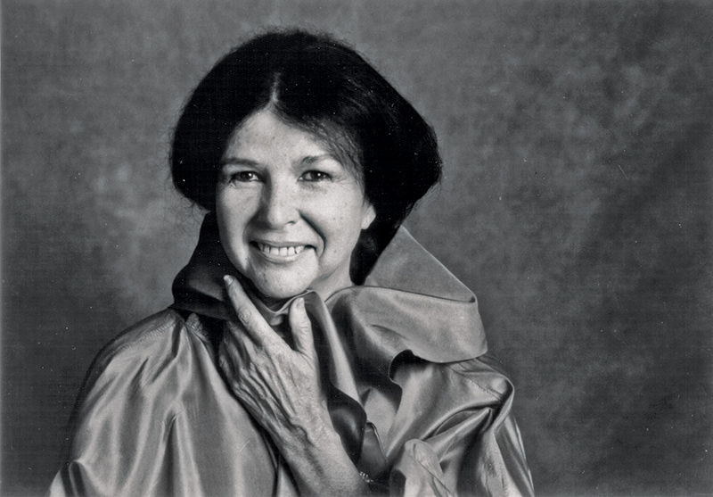 Black & white photo of a middle-aged Alanis Obomsawin. She has dark straightened hair and is wearing a satin cape.