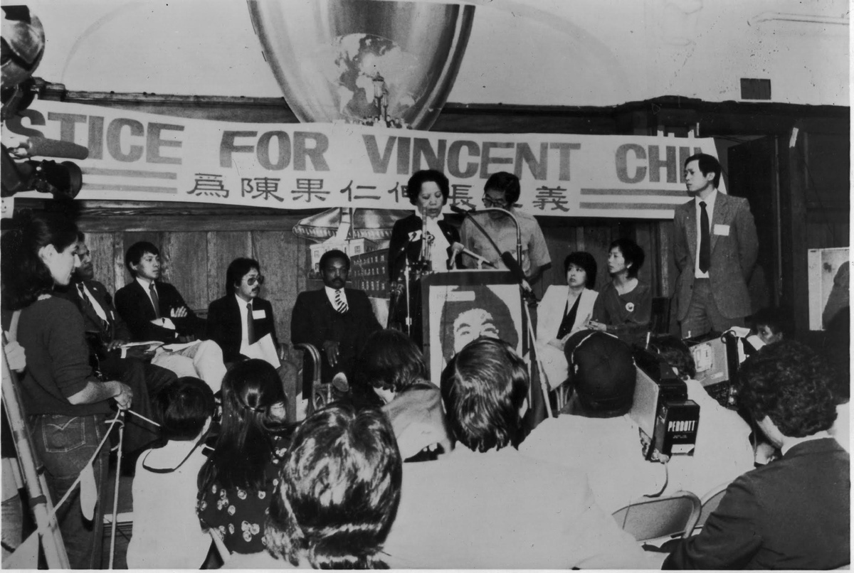 A rally for justice for Vincent Chin. His mother is speaking behind a podium. From Renee Tajima-Pena and Chritine Choy's 'Who Killed Vincent Chin?' Courtesy of Renee Tajima-Pena. 
