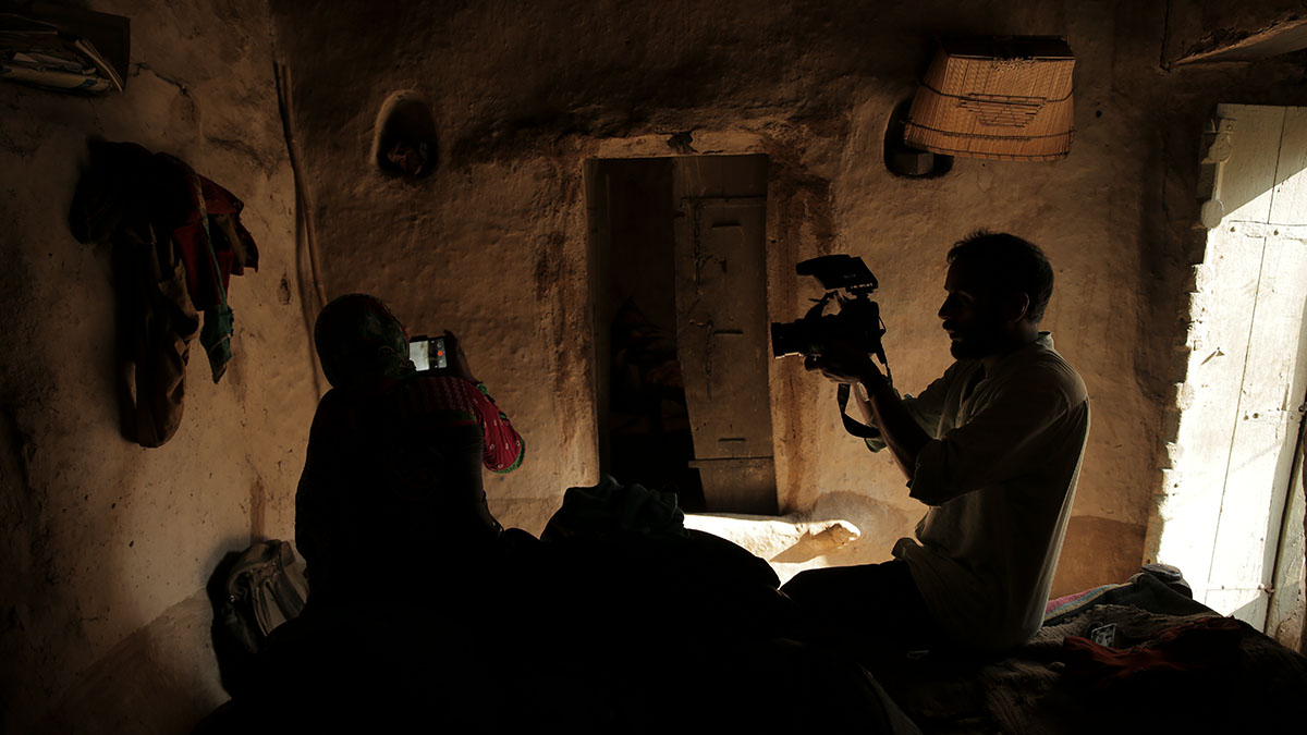 Sushmit Ghosh is a South Asian male cinematographer, seen here filming journalist Meera Devi at work. A BTS still from ‘Writing With Fire.’ Courtesy of Rintu Thomas and Sushmit Ghosh.