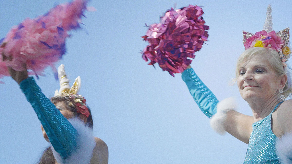 Two older white women performing a dance routine with unicorn head dresses and pompoms. From Maria Loohufvud and Love Martinsen’s ‘Calendar Girls.’ Image courtesy of Sundance Institute.