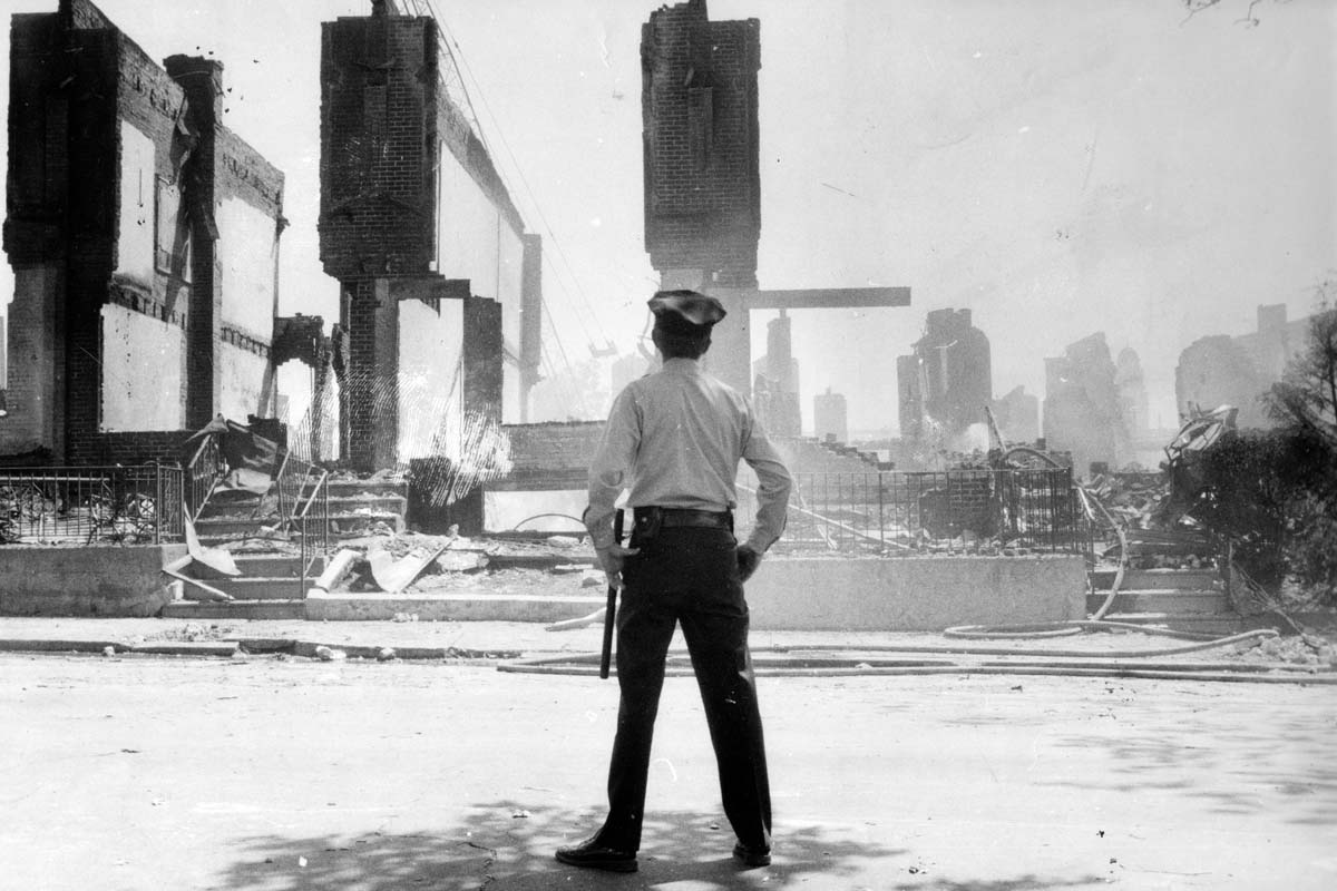 A cop on a Philadelphia street faces a row of burned buildings From 'Let the Fire Burn,' for which Nels Bangerter earned a Best Editing Awards Courtesy of Zeitgeist Films