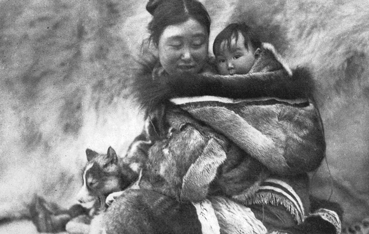 A woman with a pup looks at the baby on her back from Robert J. Flaherty's 'Nanook of the North' 