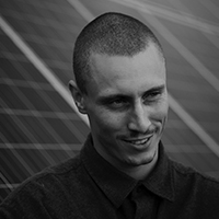 A black and white portrait of a man with a buzz cut and a dark mustache.