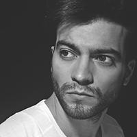 A black and white portrait of a man with darker skin and black hair and facial hair.
