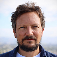 A white man with brown short hair and facial hair.